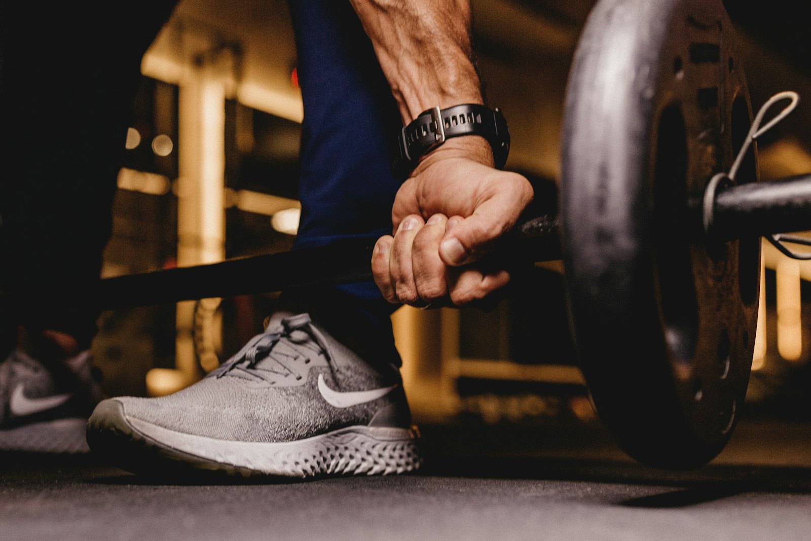 Gros plan sur une main qui saisit une barre, chaussure de sport au sol